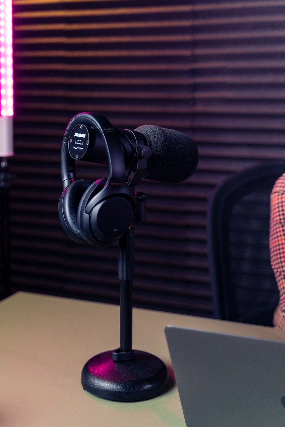 Professional microphone and headphones on a desk in a studio.